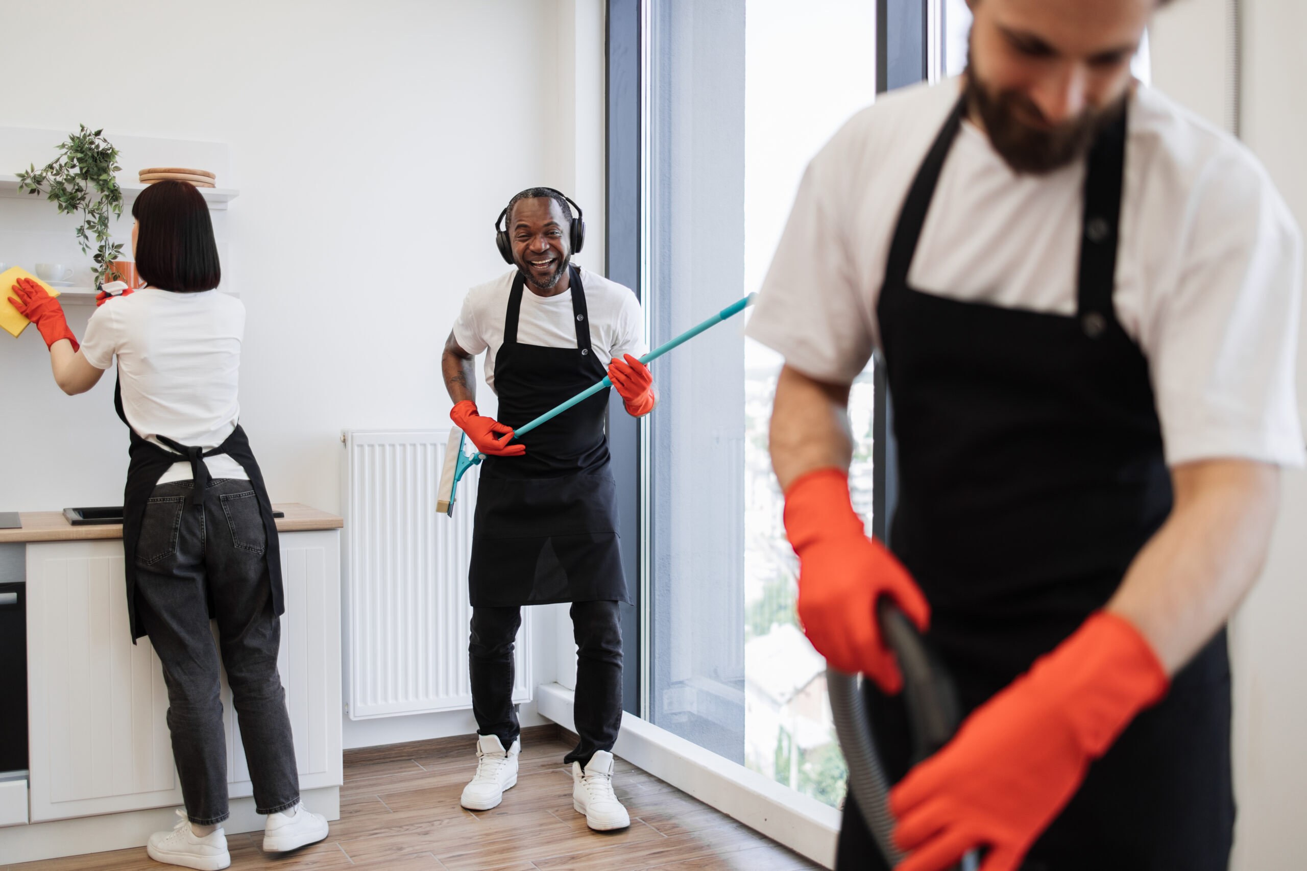 African male worker washes windows, having fun while holding mop like guitar.