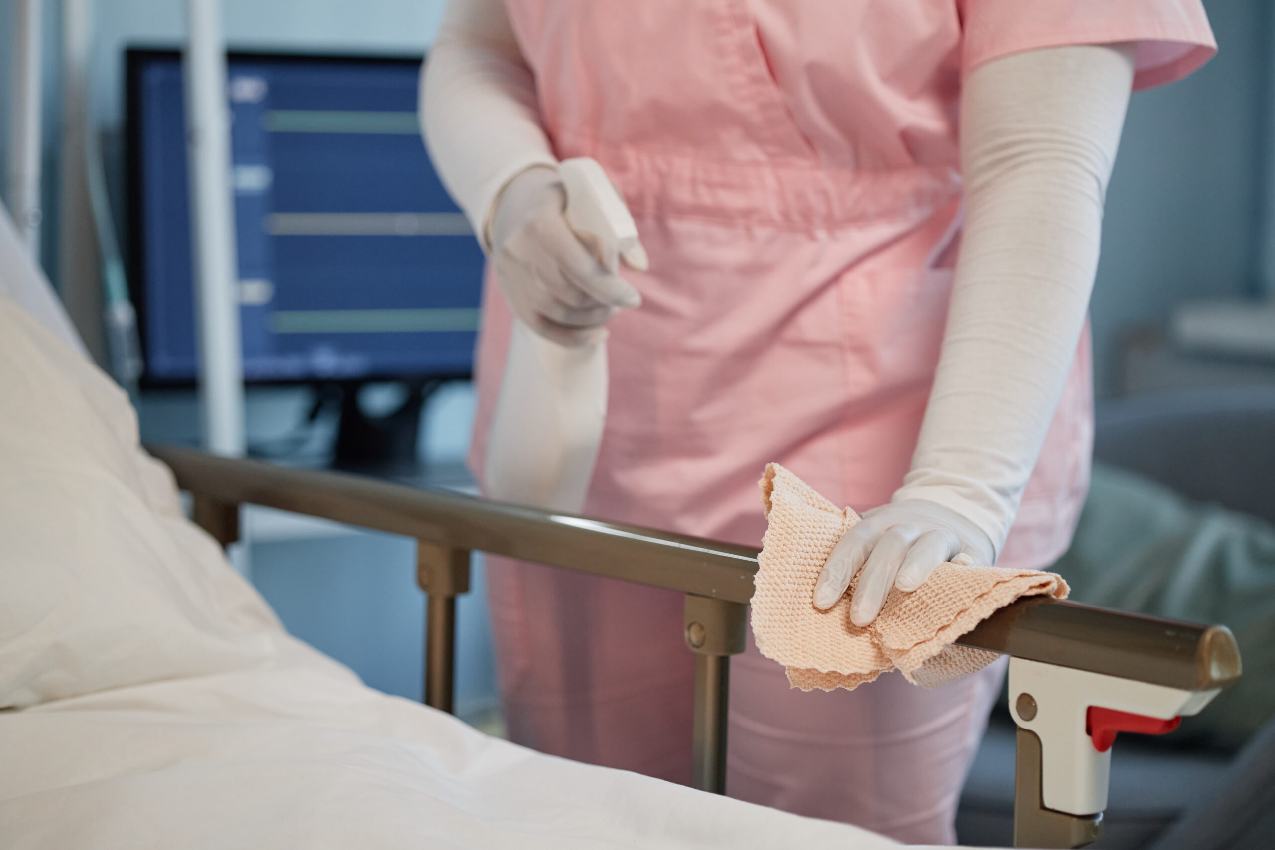 Cleaning Hospital Bed with Sanitizing Cloth in Healthcare Facility