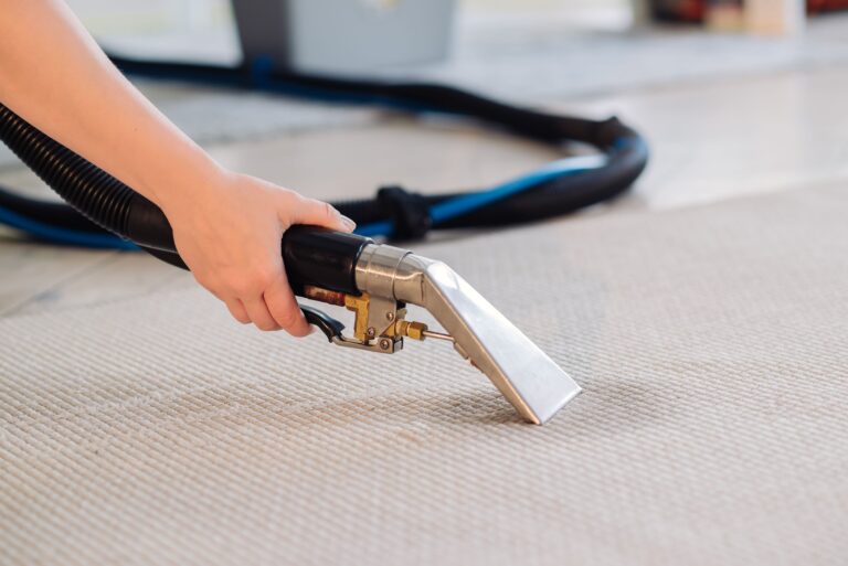 Housekeeper holding a washing vacuum cleaner and cleaning dirty carpet with stain with detergent